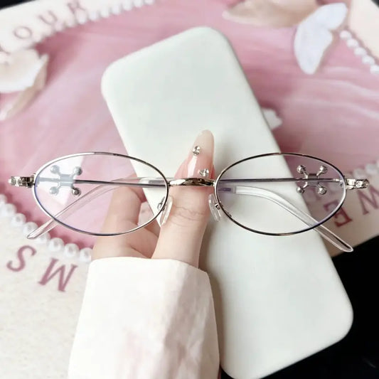 Upgrade your edgy look with our Y2K silver oval metal glasses! Featuring a classic narrow oval frame with iconic chrome cross emblems on the lenses and dazzling rhinestone-studded hinges. Perfect for cyber y2k, gothic grunge & bayonetta aesthetics. Shop today!